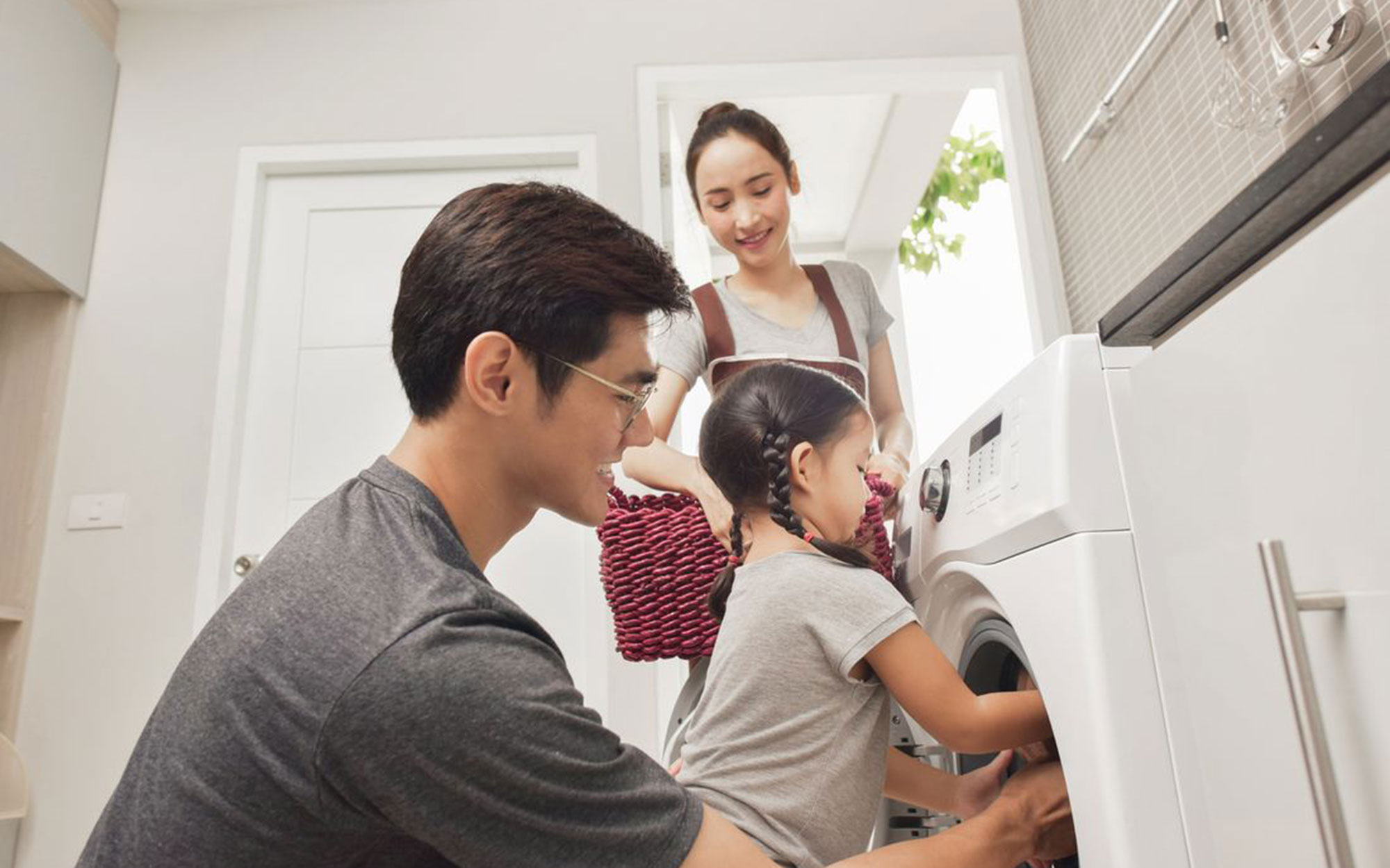 Family in the laundry loading the washing machine 