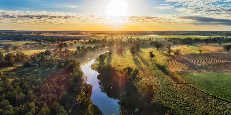 Macquarie river in Dubbo near Dundullmal homestead and farm fields in aerial sunrise scenic view.