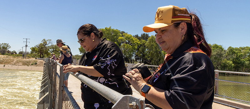 Two women yarning above a river