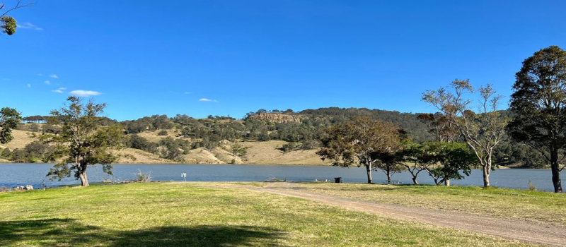 View of dam on a sunny day with trees surrounding 