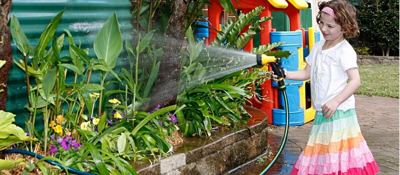 Girl watering gardening using water from a rainwater tank