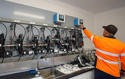 Man in high vis in front of a water treatment set up 