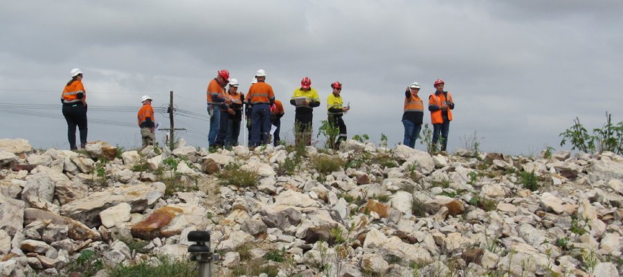 People in hi vis standing on top of a rock-covered dam 