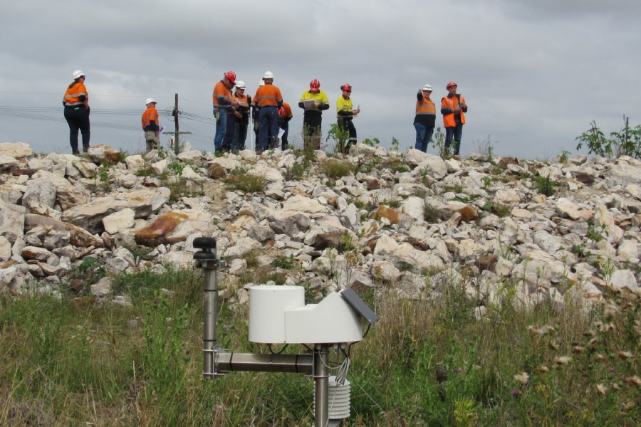 People in hi vis standing on top of a rock-covered dam with instrumentation in foreground
