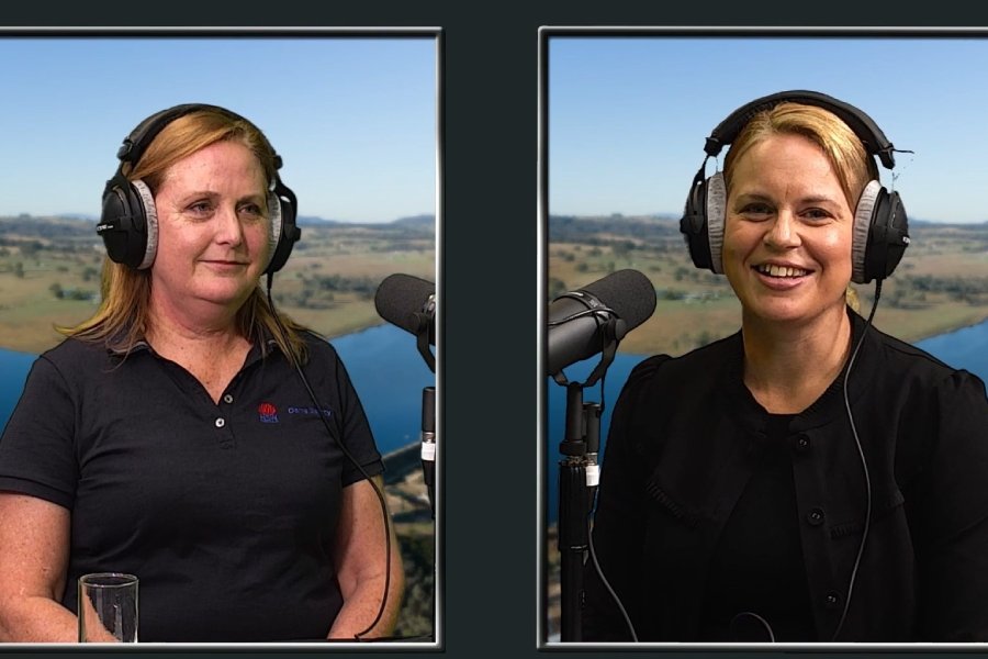 Two women wearing headphone speaking into microphones
