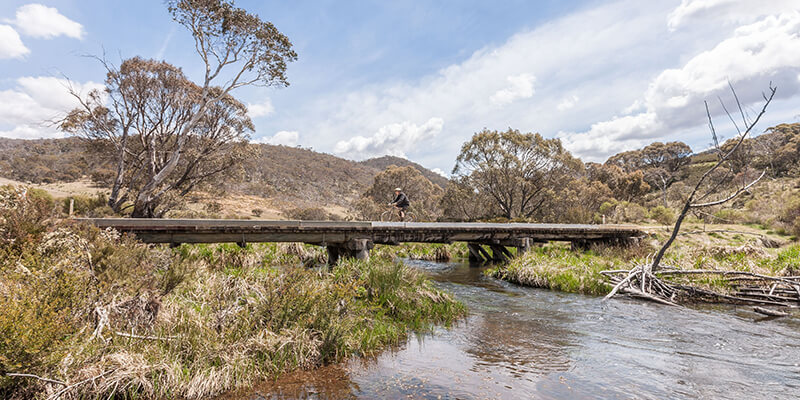 A male teenage tourist rides his bike along the Murrumbidgee Bridge Crossing on the Murrumbidgee Ride near Pockets Saddle Road in Kosciuszko National Park.