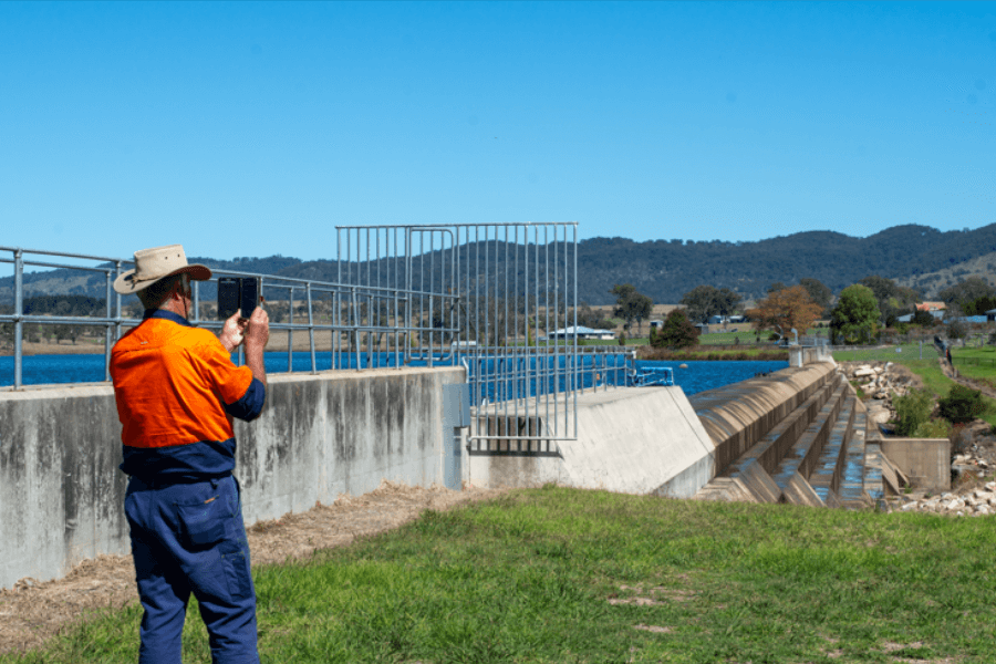 Man in high vis taking photo of dam with phone