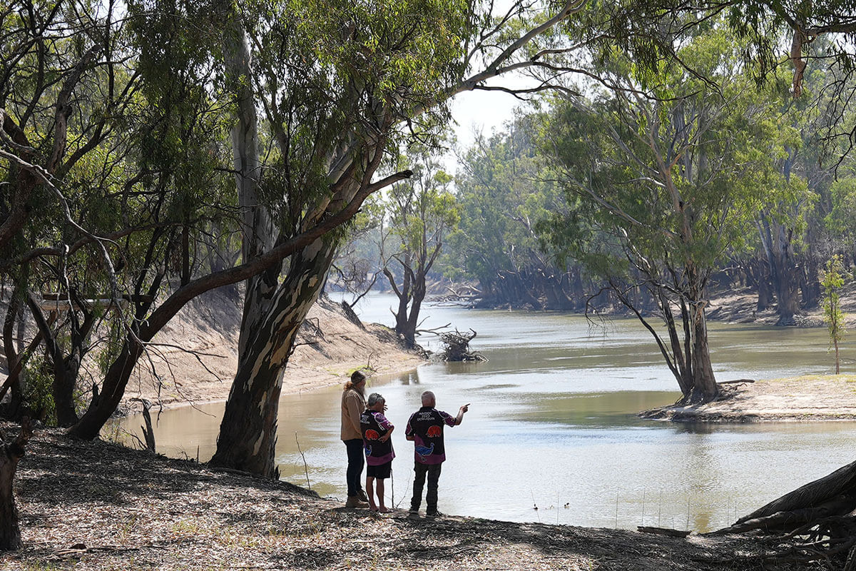 3 aboriginal people standing on the banks of the river 