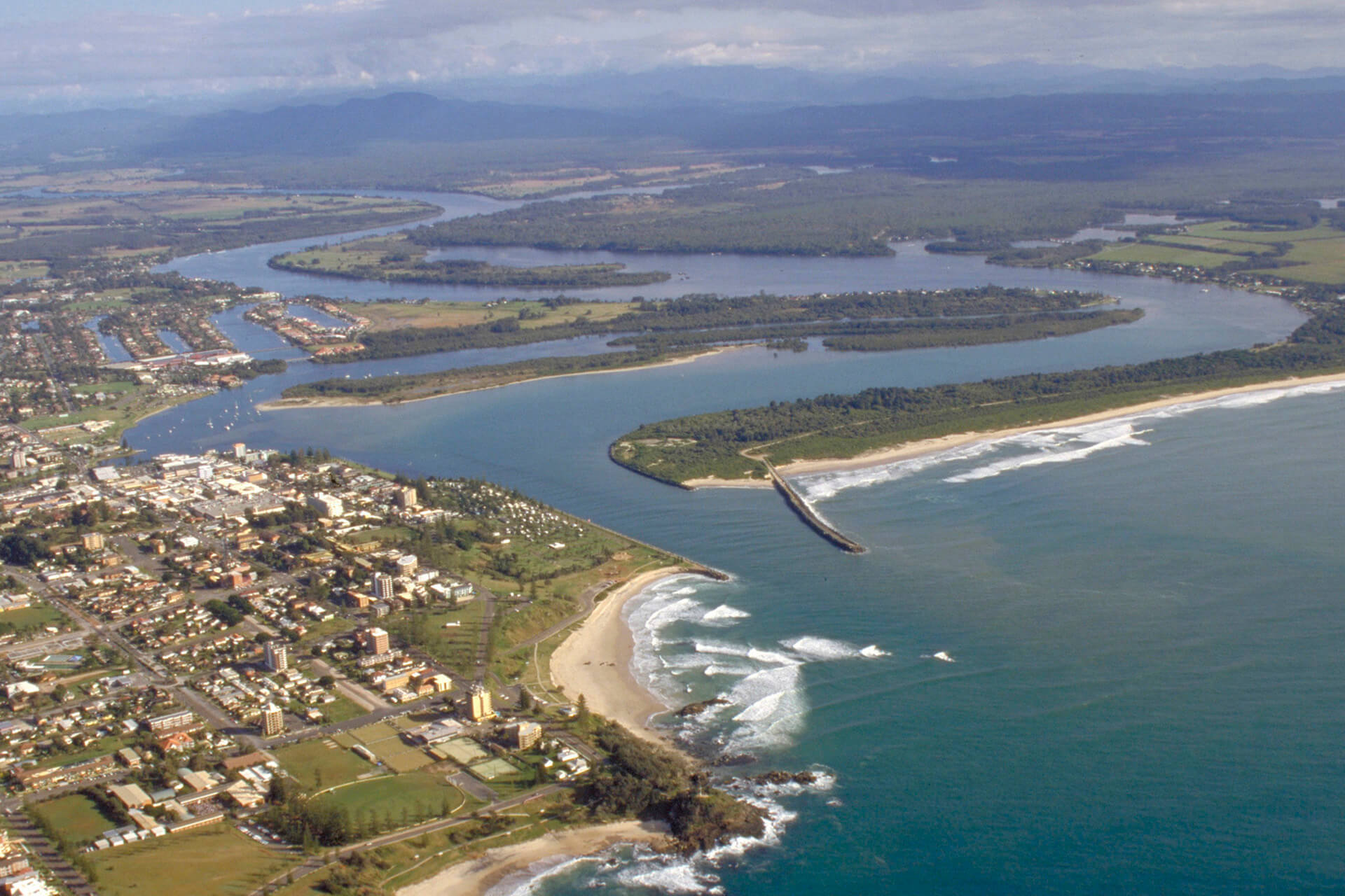 An aerial photos of a town with lots of small buildings at the mouth of a winding river