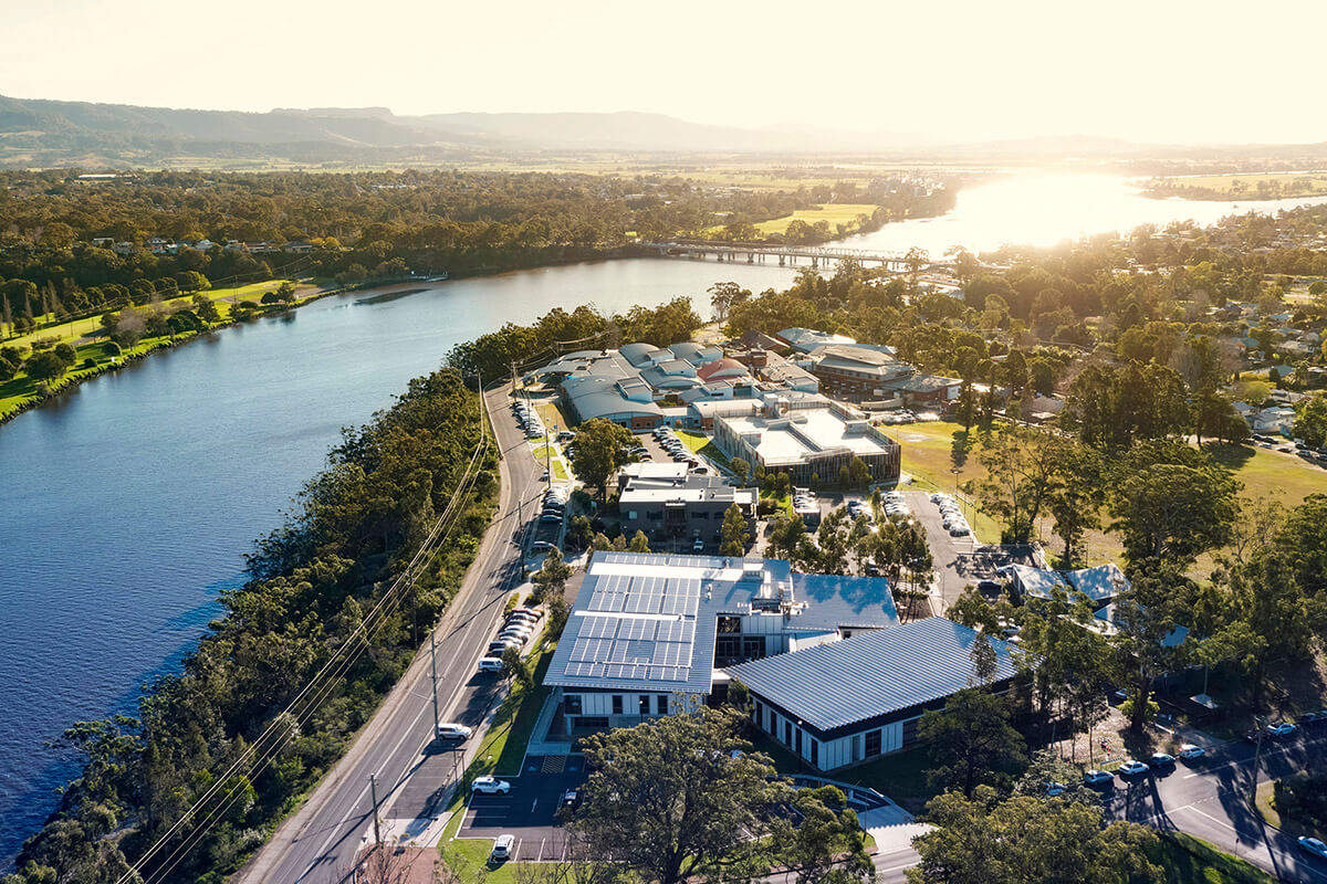 Aerial view of the Shoalhaven river at sunset. There is a road and several buildings on the bank of the river