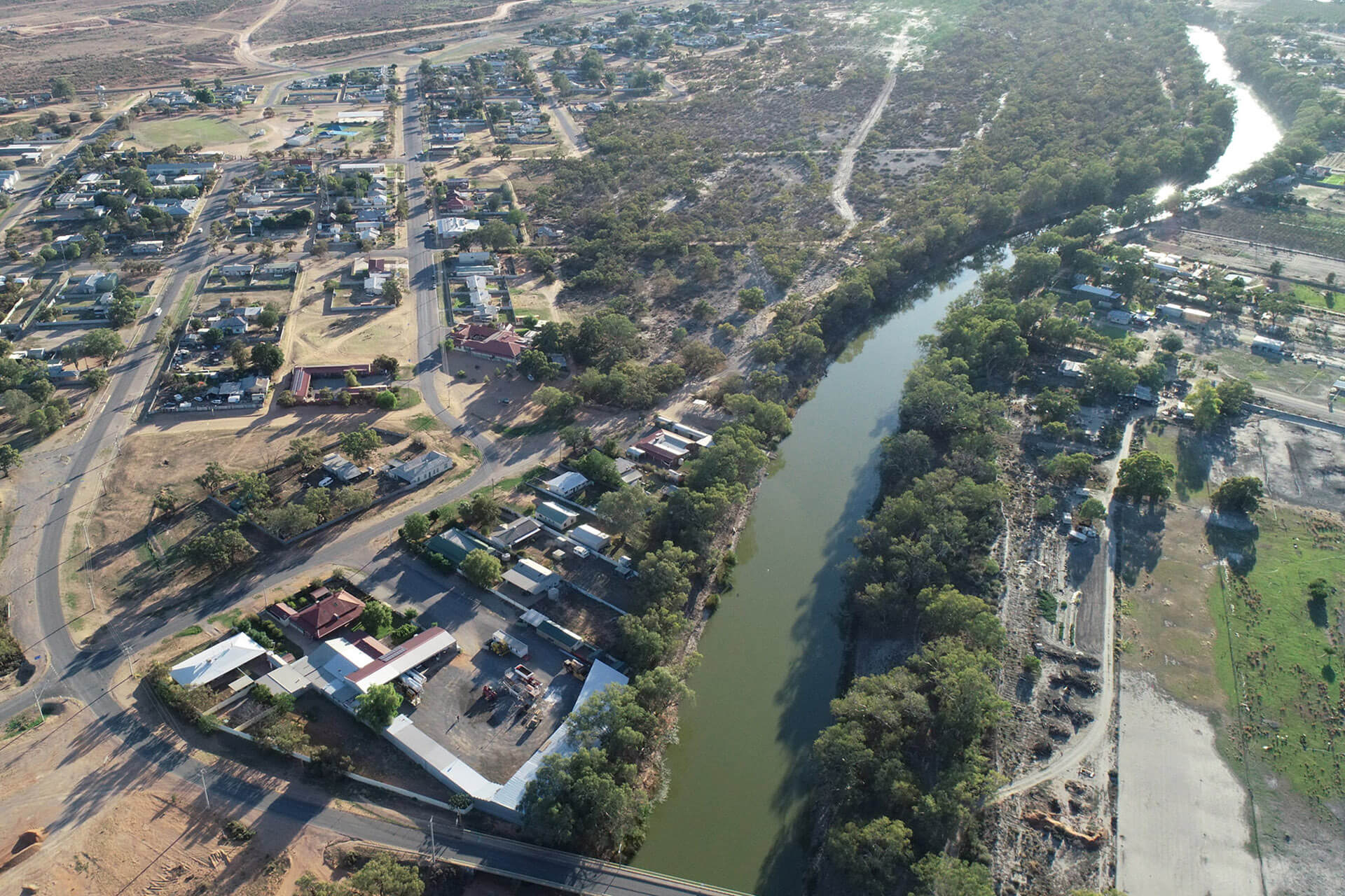 An aerial photo of a river, some trees. and buildings on dry ground. Menindee town in 2020 and the Darling River.