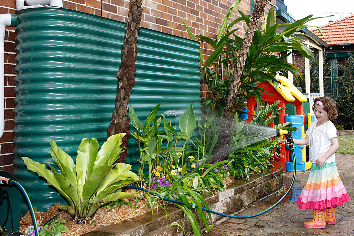 Young girl watering a garden with a hose