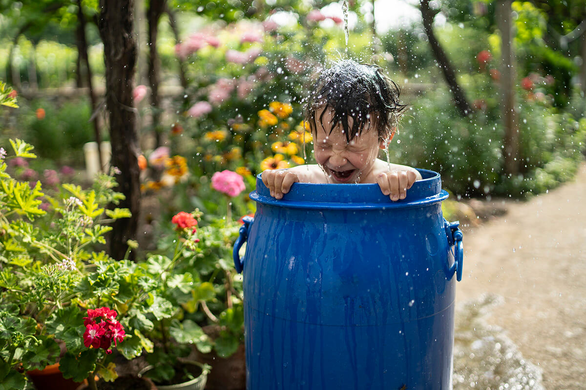 Child in a blue barrel of water in a garden