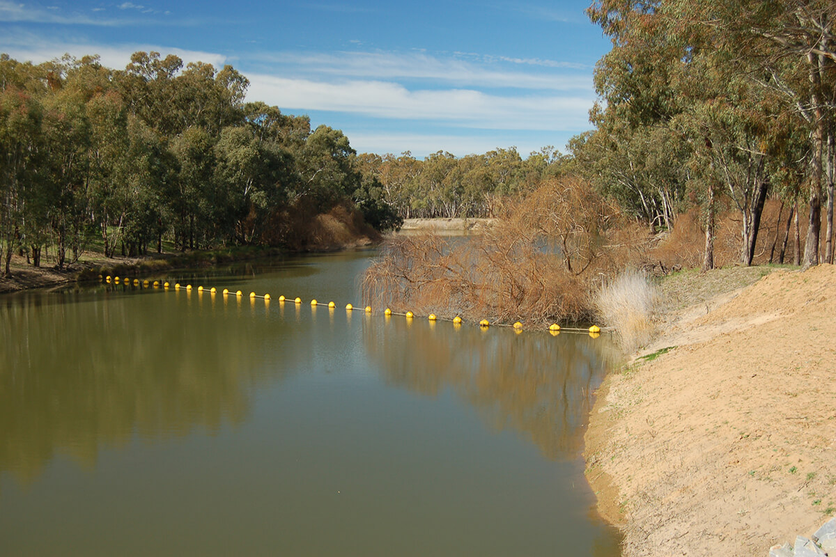 River with yellow buoy chain strung across it 